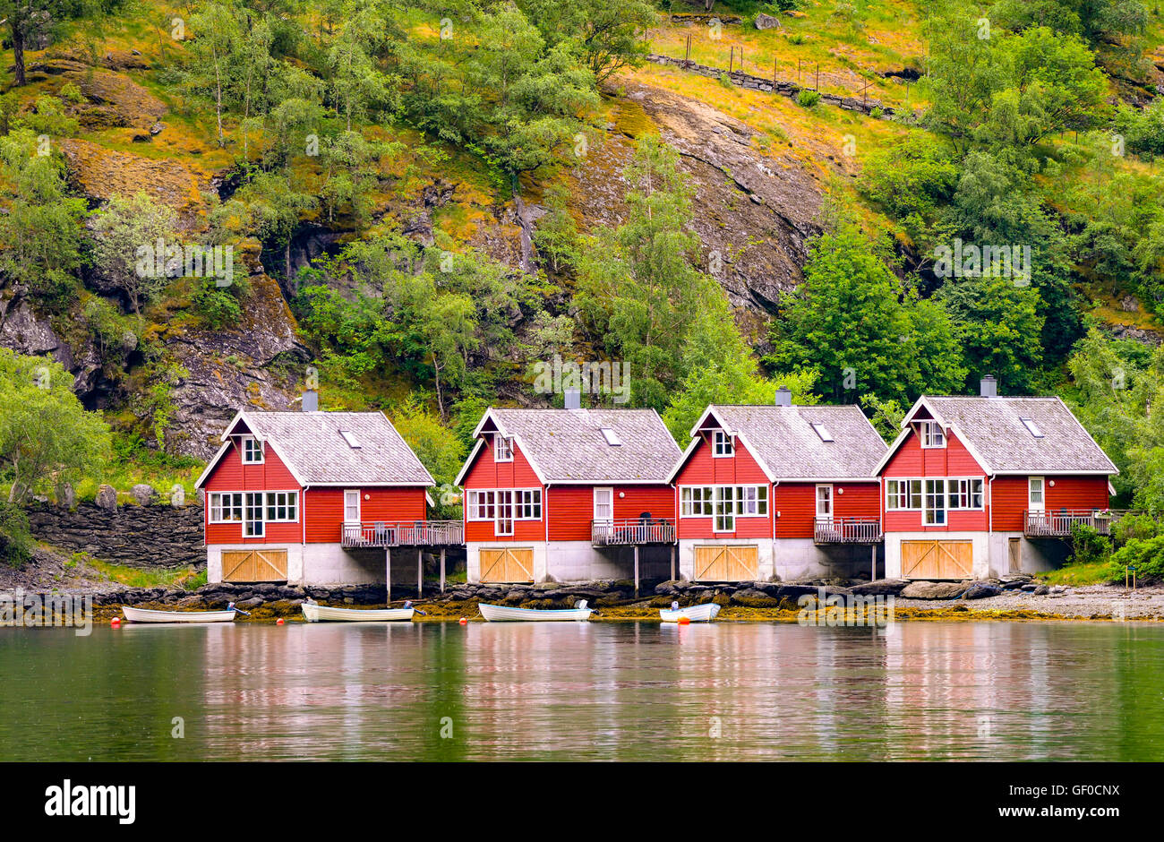 Fishermans huts and boats reflecting in Flam Harbour and Marina surrounded by mountain forest. Flam, Norway Stock Photo