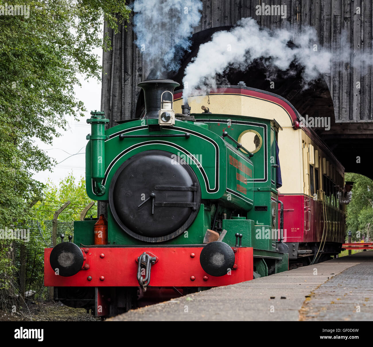 Green restored steam locomotive train pulls out of a station at the ...