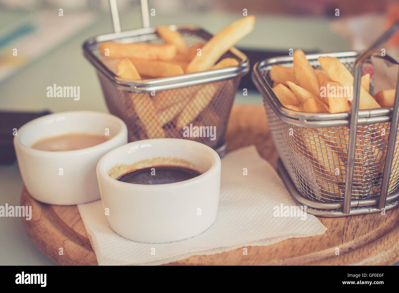 French fries with sauces served on round wooden board. Toned image Stock Photo