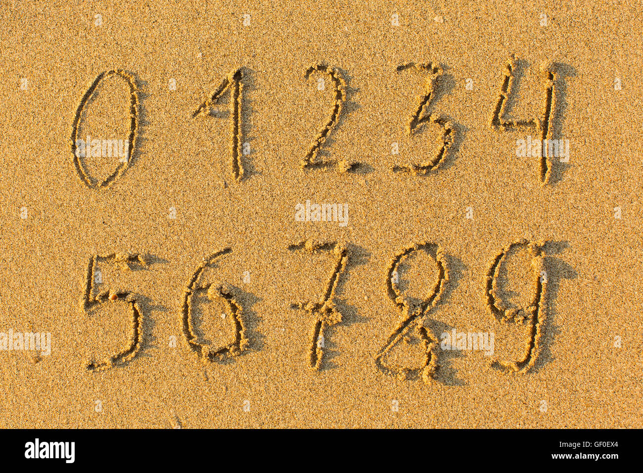 Numbers from 0 to 9 drawn on the sand to the sea. Stock Photo