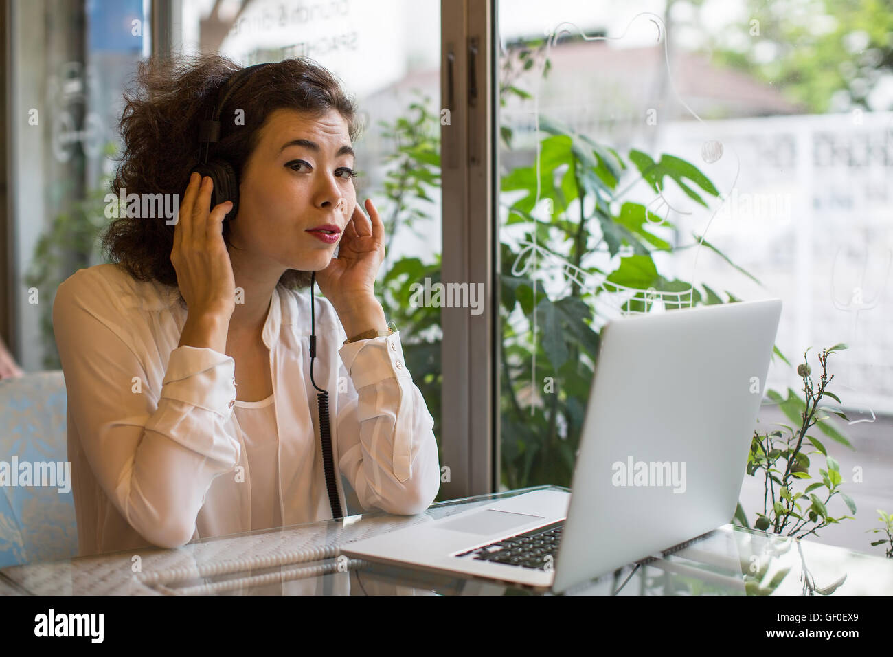 Young asian woman in headphones with a laptop in a cafe. Stock Photo