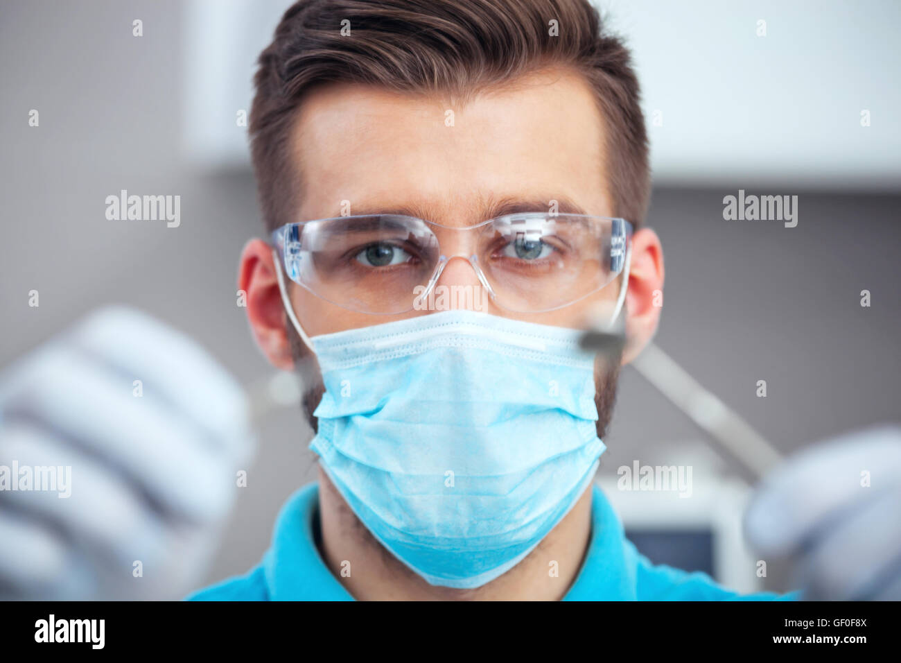 Dentist in mask and protective eyeglasses ready to start dental checkup. Stock Photo