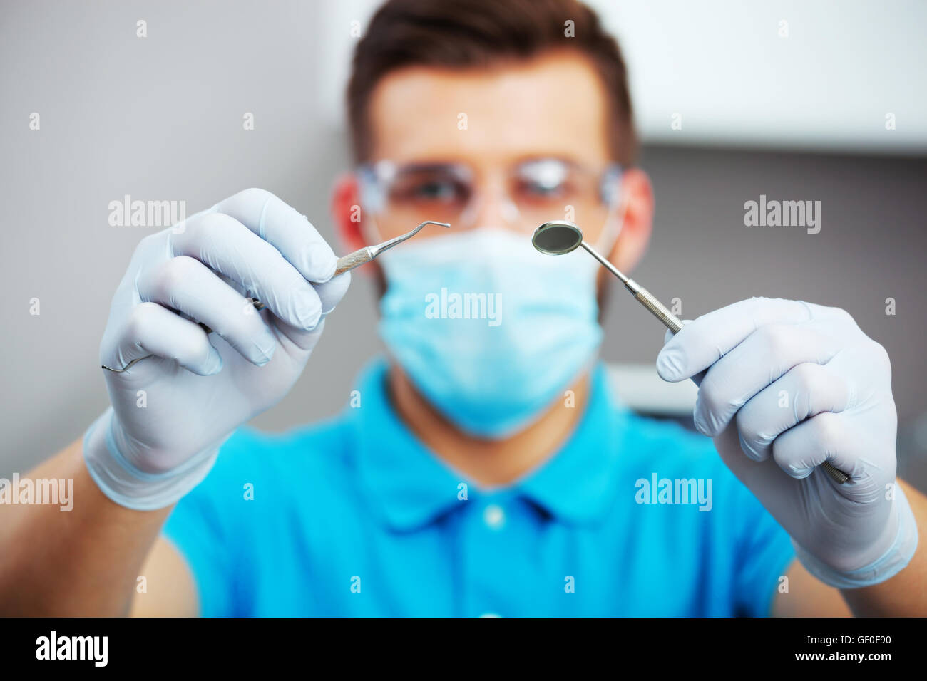 Dentist in mask and protective eyeglasses ready to start dental checkup. Focus on hands. Stock Photo