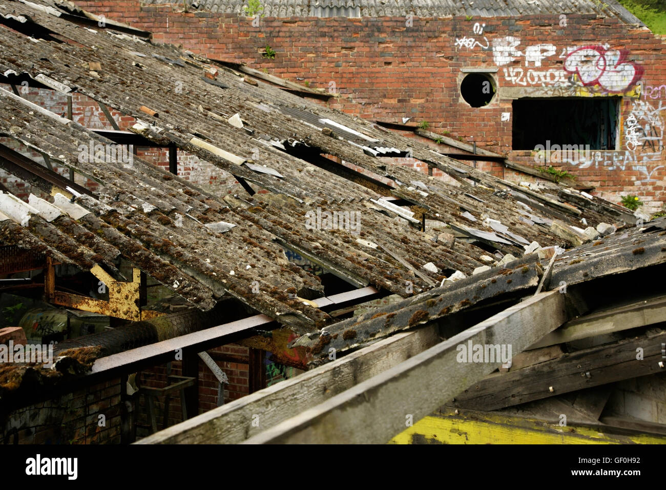 Damaged corrugated asbestos roofing on abandoned industrial building. Stock Photo