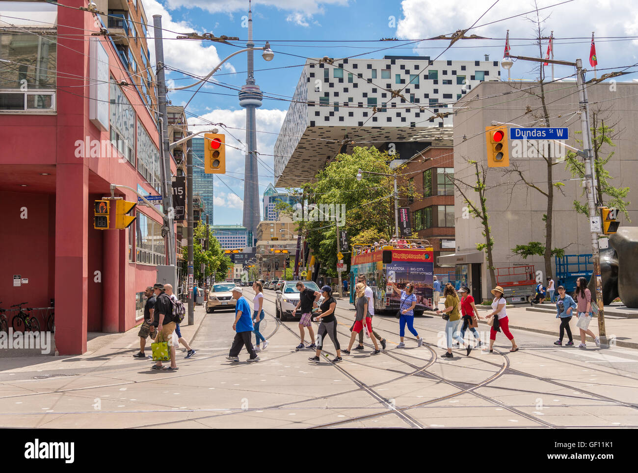 Dundas and Mccaul corner in Toronto with people walking in the crosswalk and CN tower in the background Stock Photo