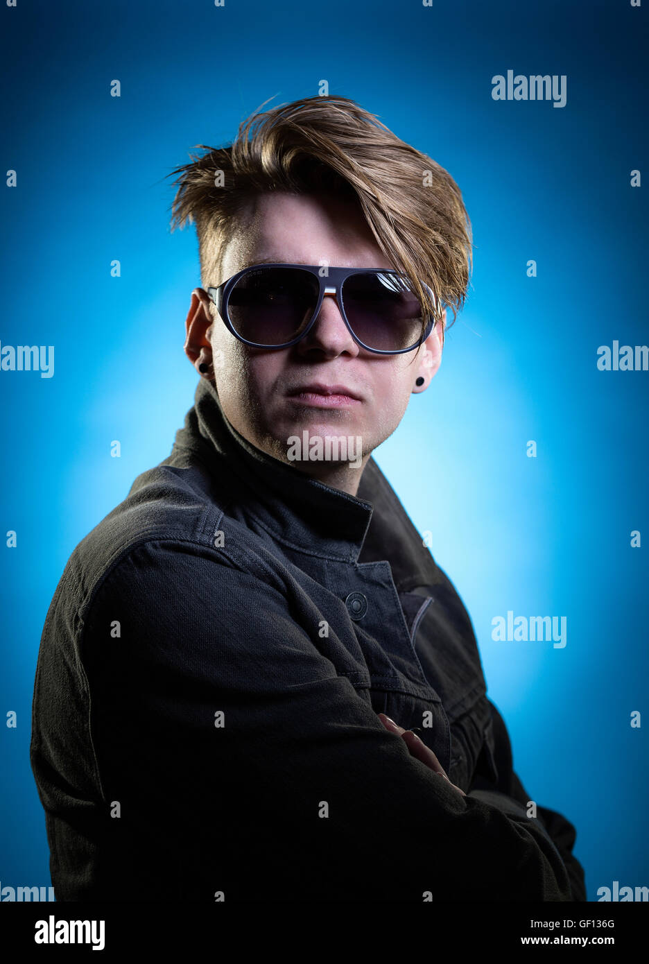 Male model portrait, sunglasses, hair, styling, fashion, blue background Stock Photo