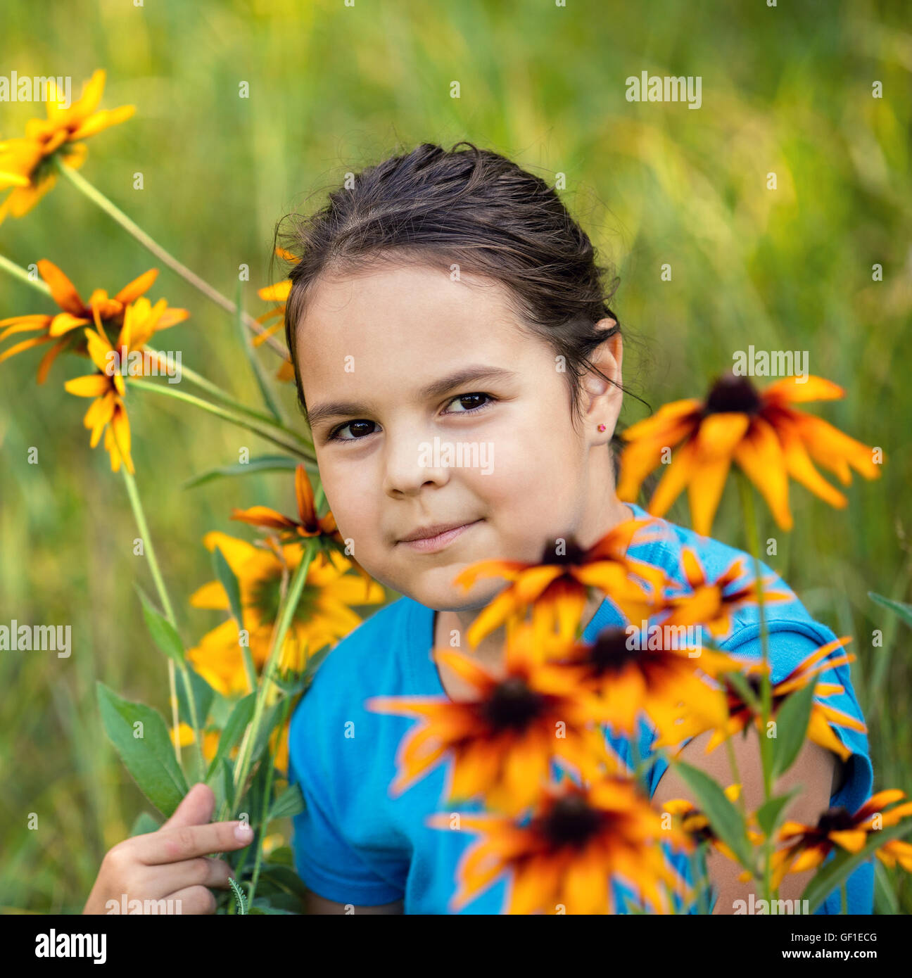 portrait of smiling little girl walking on the flower meadow Stock Photo