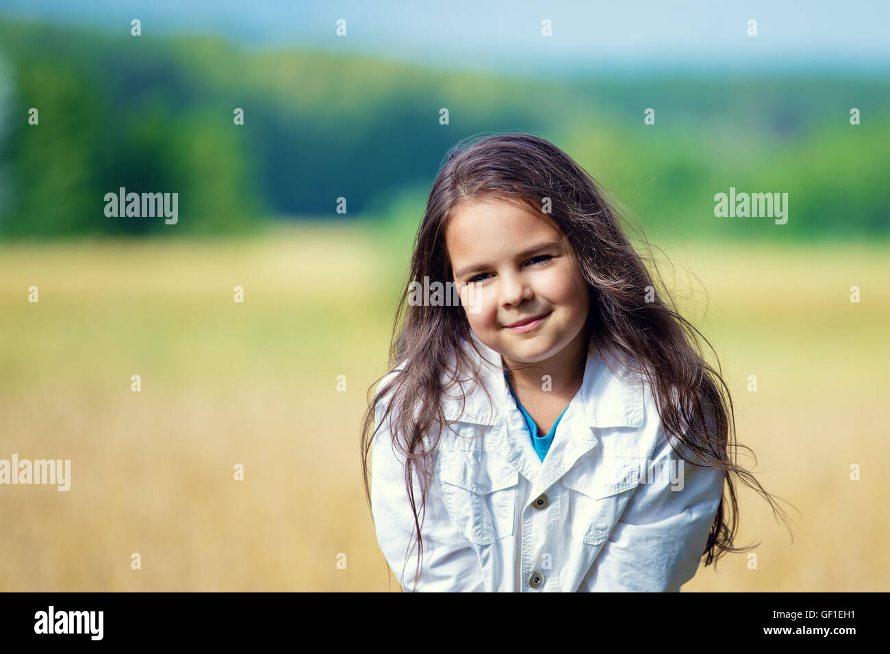 Portrait of cute little girl with brown long hair in wheat field Stock Photo