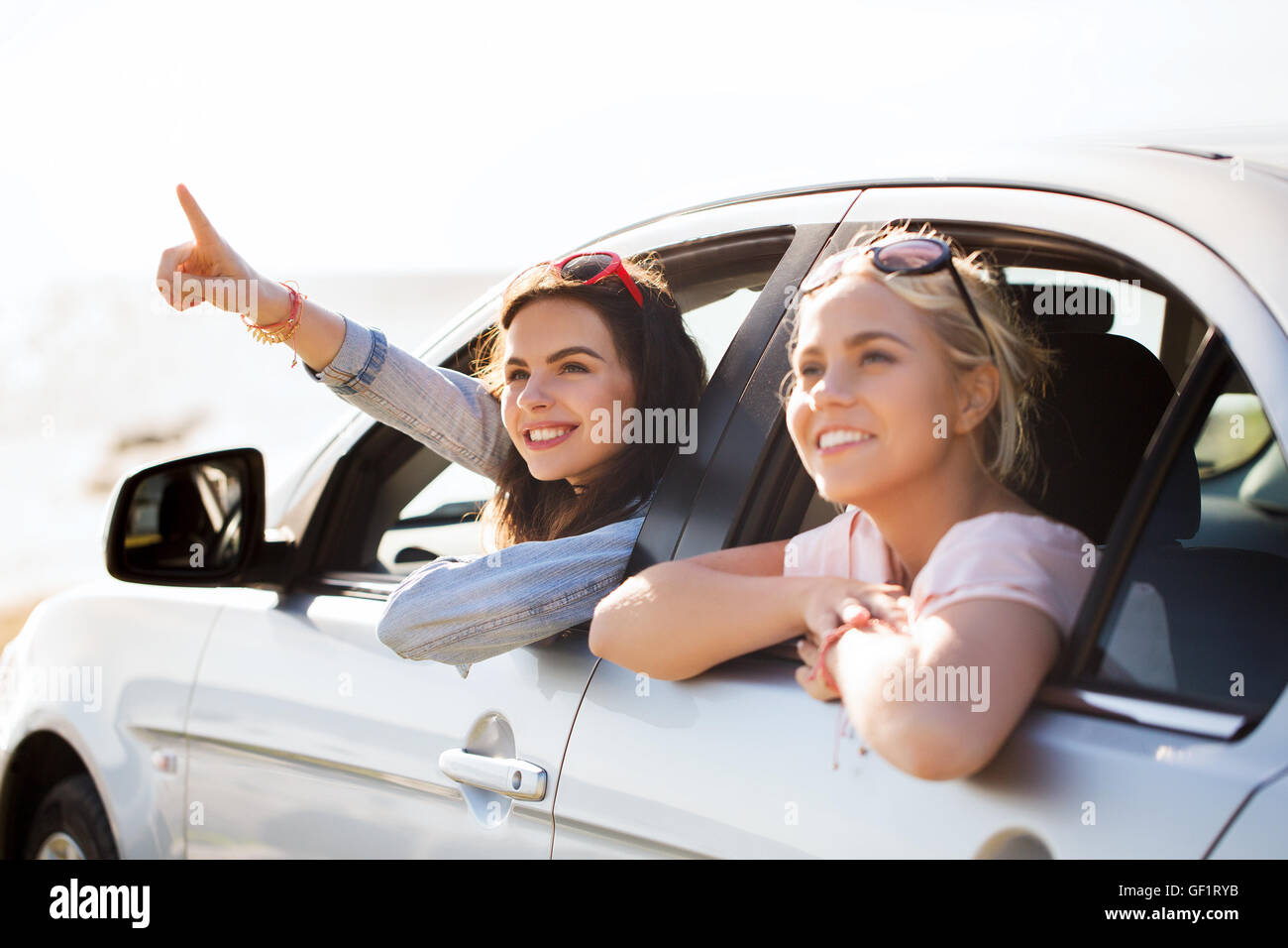 happy teenage girls or women in car at seaside Stock Photo - Alamy