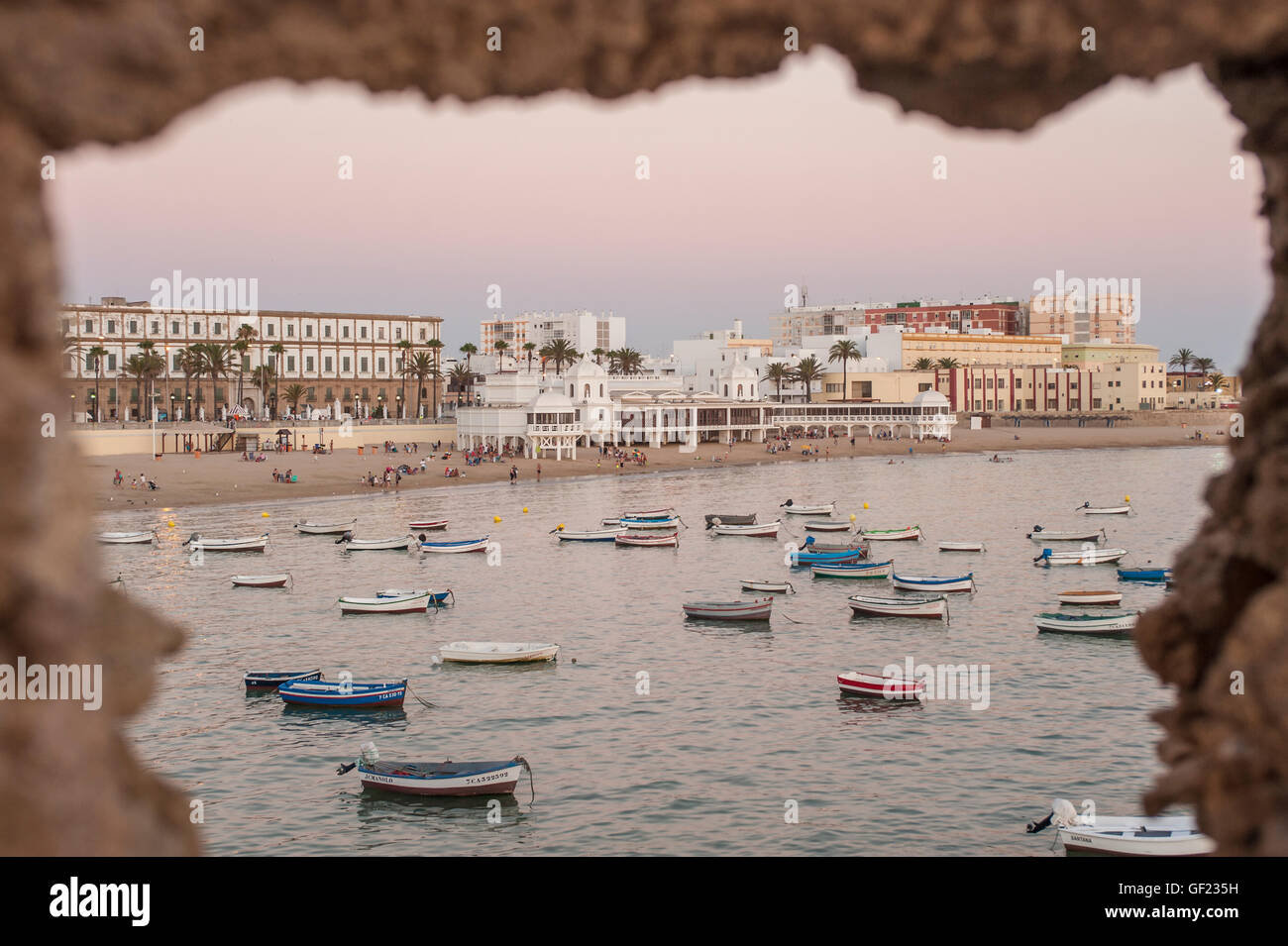 View of La Caleta beach, seen through the ramparts of the Castillo de Santa Catalina fortress, at sunset.    La Caleta is a smal Stock Photo