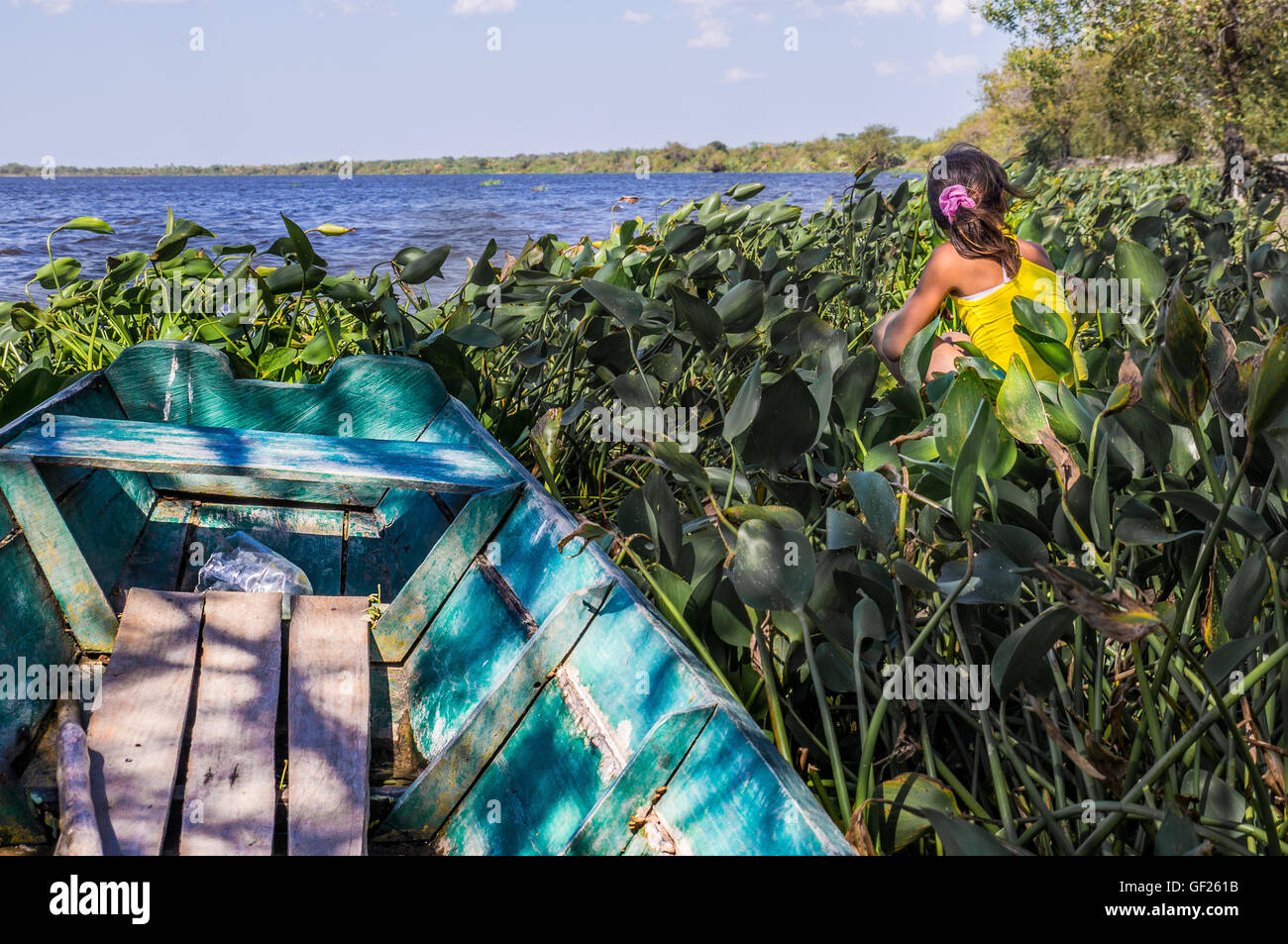 Puerto Pollo, Paraguay on August 8, 2015: An indigenous girl sitting next to a small fishermen's boat in Puerto Pollo at Rio Par Stock Photo
