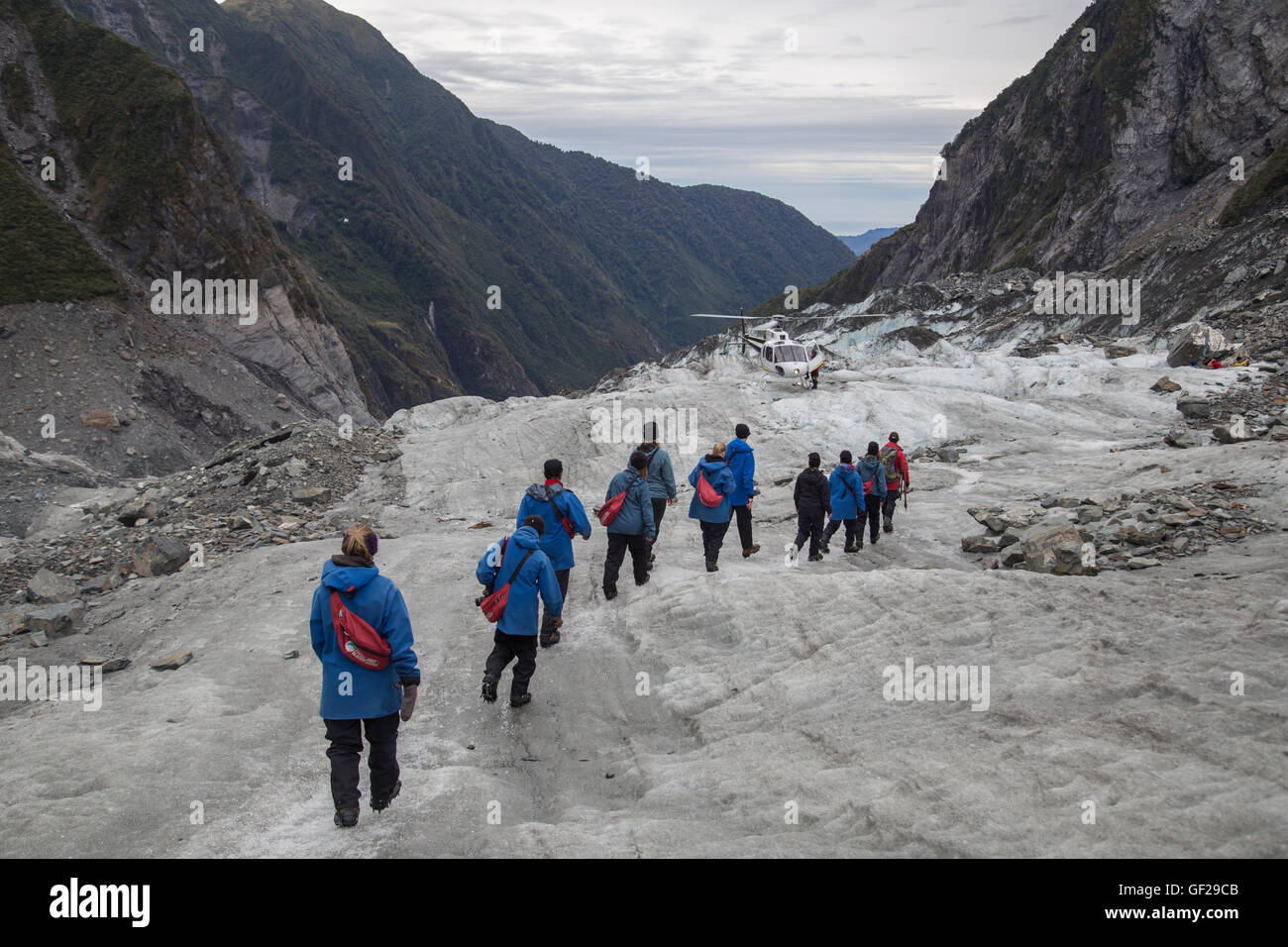 Franz Josef, New Zealand - March 22, 2015: A group of tourists hiking towards a helicopter on the Franz Josef Glacier. Stock Photo