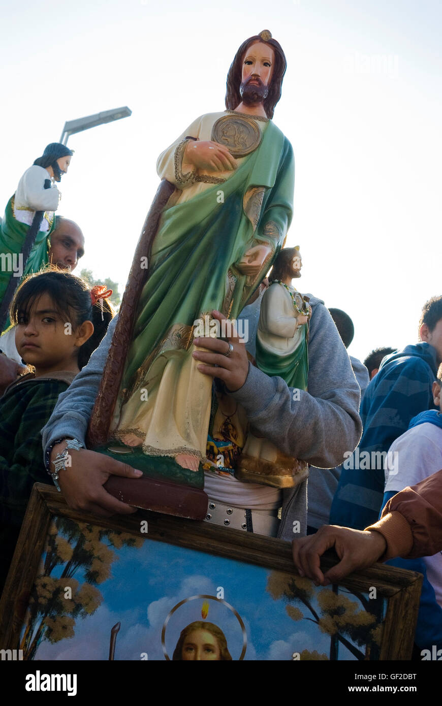 A young woman carrying statues of Saint Jude Thaddeus, the patron of lost causes, walks in a crowd on the saint's feast day. Stock Photo