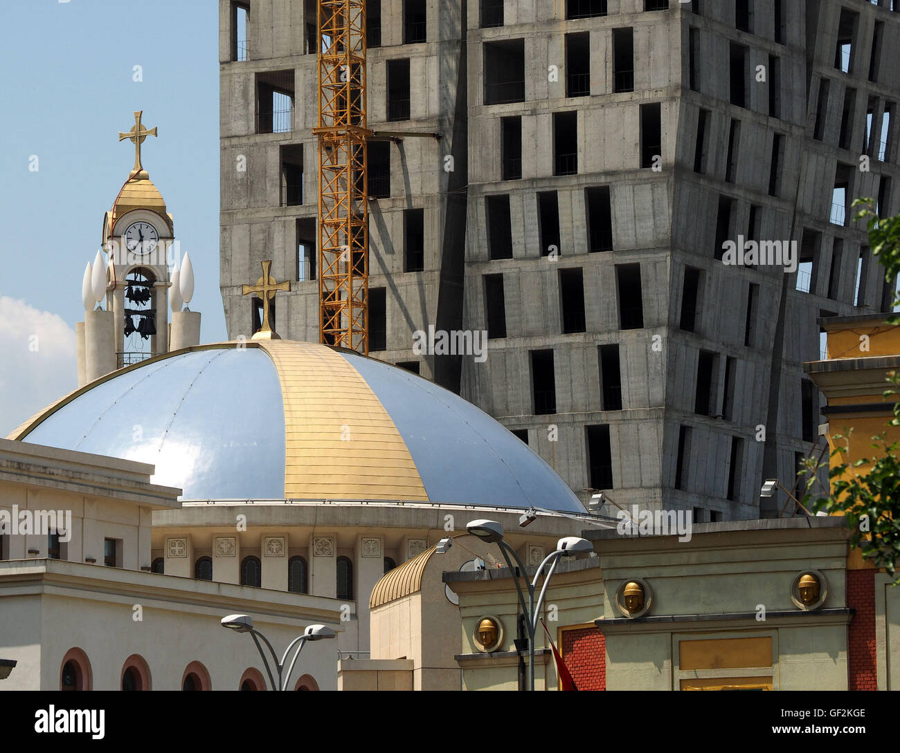 Juxtaposition of traditional domed orthodox church and base of new skyscraper building in Albanian capital Tirana in the Balkans Stock Photo