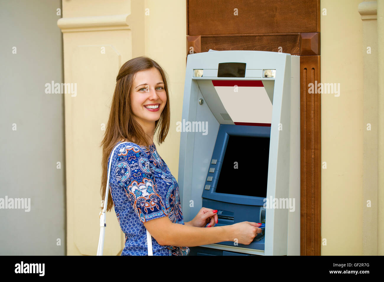 Brunette young lady using an automated teller machine. Woman withdrawing money or checking account balance Stock Photo
