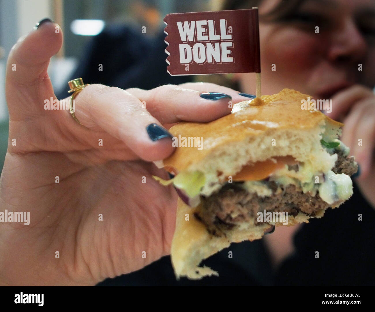 Previously unissued photo dated 13/03/15 of a woman holding a burger at a Byron restaurant in east London, as dozens of workers at the burger chain have been arrested in a swoop by immigration officials. Stock Photo