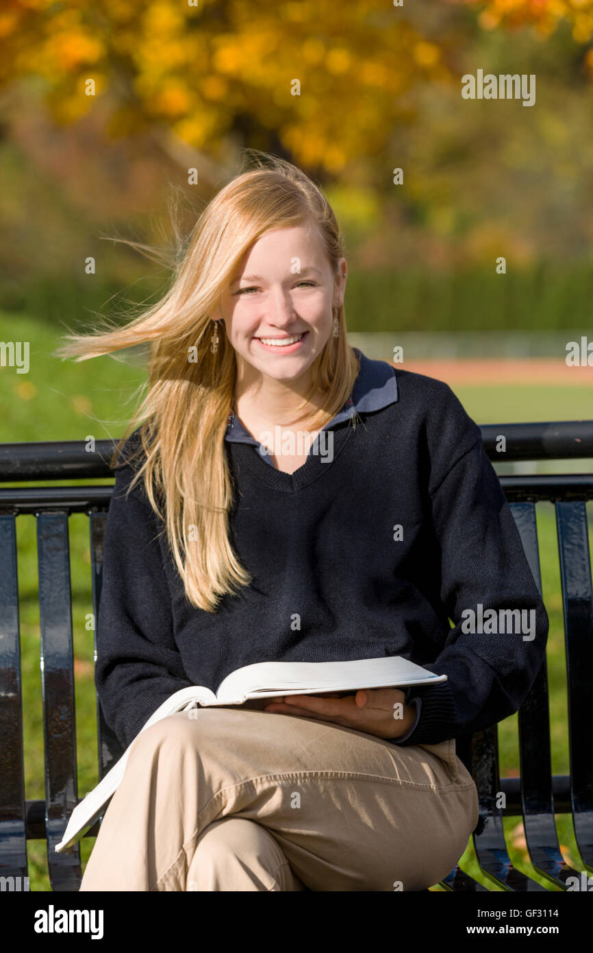 Candid portrait of a teenage girl on a bench, private school campus. Stock Photo