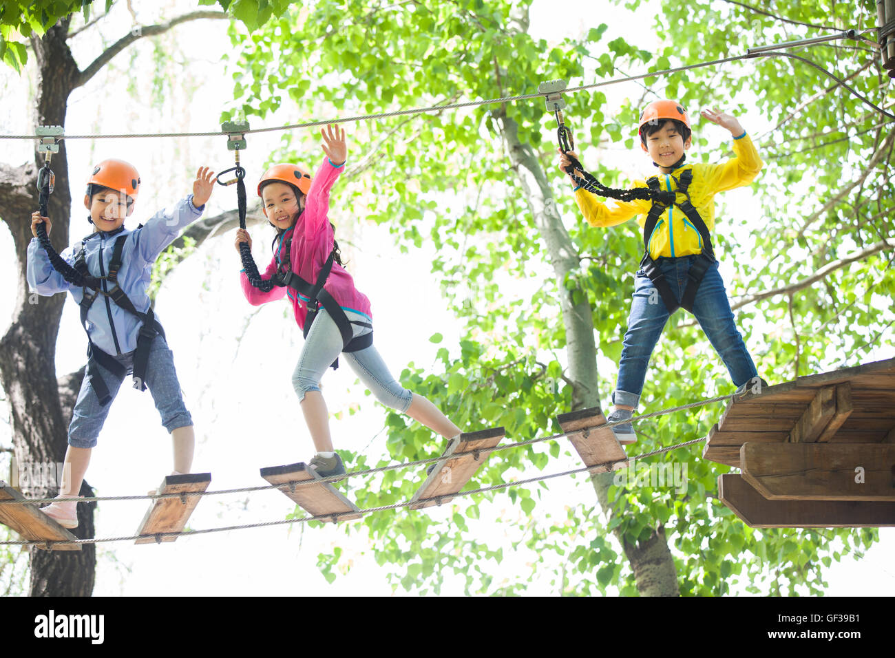 Happy Chinese children playing in tree top adventure park Stock Photo