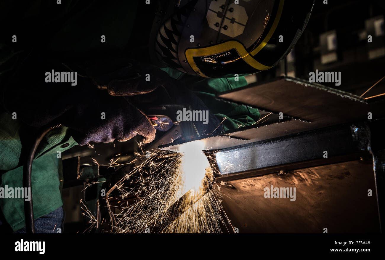 high speed plasma cutting slag sparks and smoke stream arc one helmet mig weld steel stick tig miller lincold electric dirt mo Stock Photo