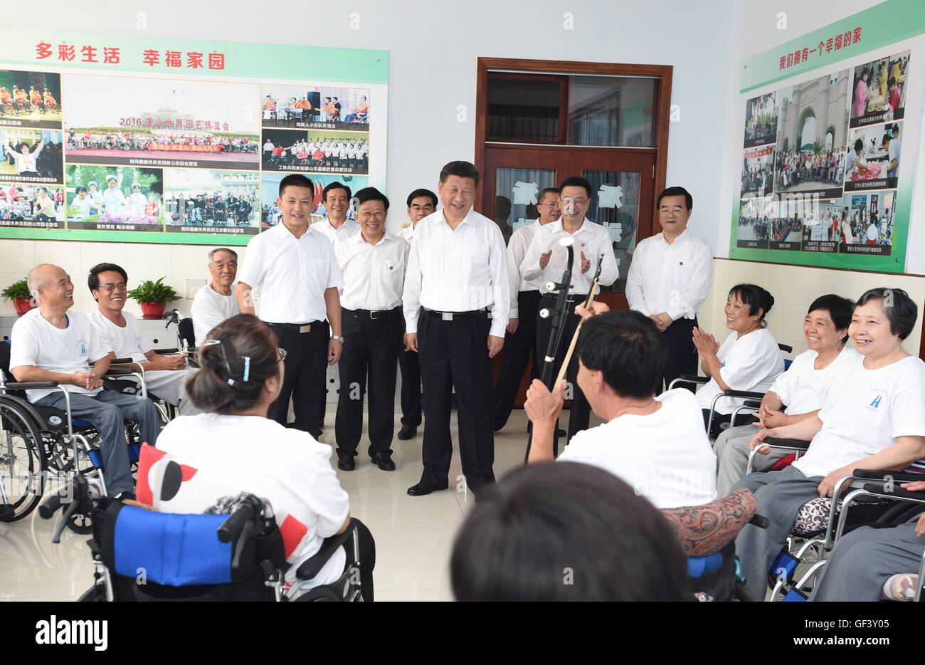 Tangshan, China's Hebei Province. 28th July, 2016. Chinese President Xi Jinping (C), who is also general secretary of the Communist Party of China (CPC) Central Committee and chairman of the Central Military Commission (CMC), watches paraplegic patients singing accompanied by Erhu, a Chinese two-stringed musical instrument, at the city's paraplegic rehabilitation center in Tangshan, north China's Hebei Province, July 28, 2016. Credit:  Xie Huanchi/Xinhua/Alamy Live News Stock Photo