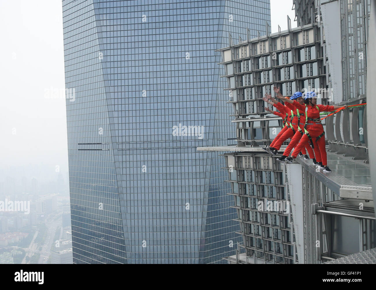 Shanghai, China. 28th July, 2016. Safety instructors give a demonstration  on a skywalk 340 meters above the ground at Jinmao Tower in Shanghai, east  China, July 28, 2016. A fenceless, glass skywalk