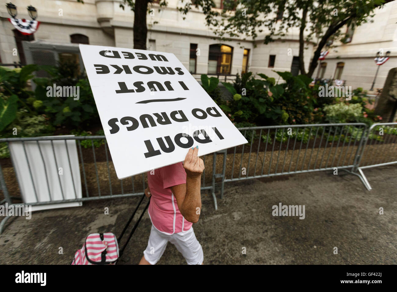 Philadelphia, USA. 28th July, 2016. A protester puts their sign over their head on a rainy day outside Philadelphia City Hall on the final day of the Democratic National Convention. Credit:  John Orvis/Alamy Live News Stock Photo