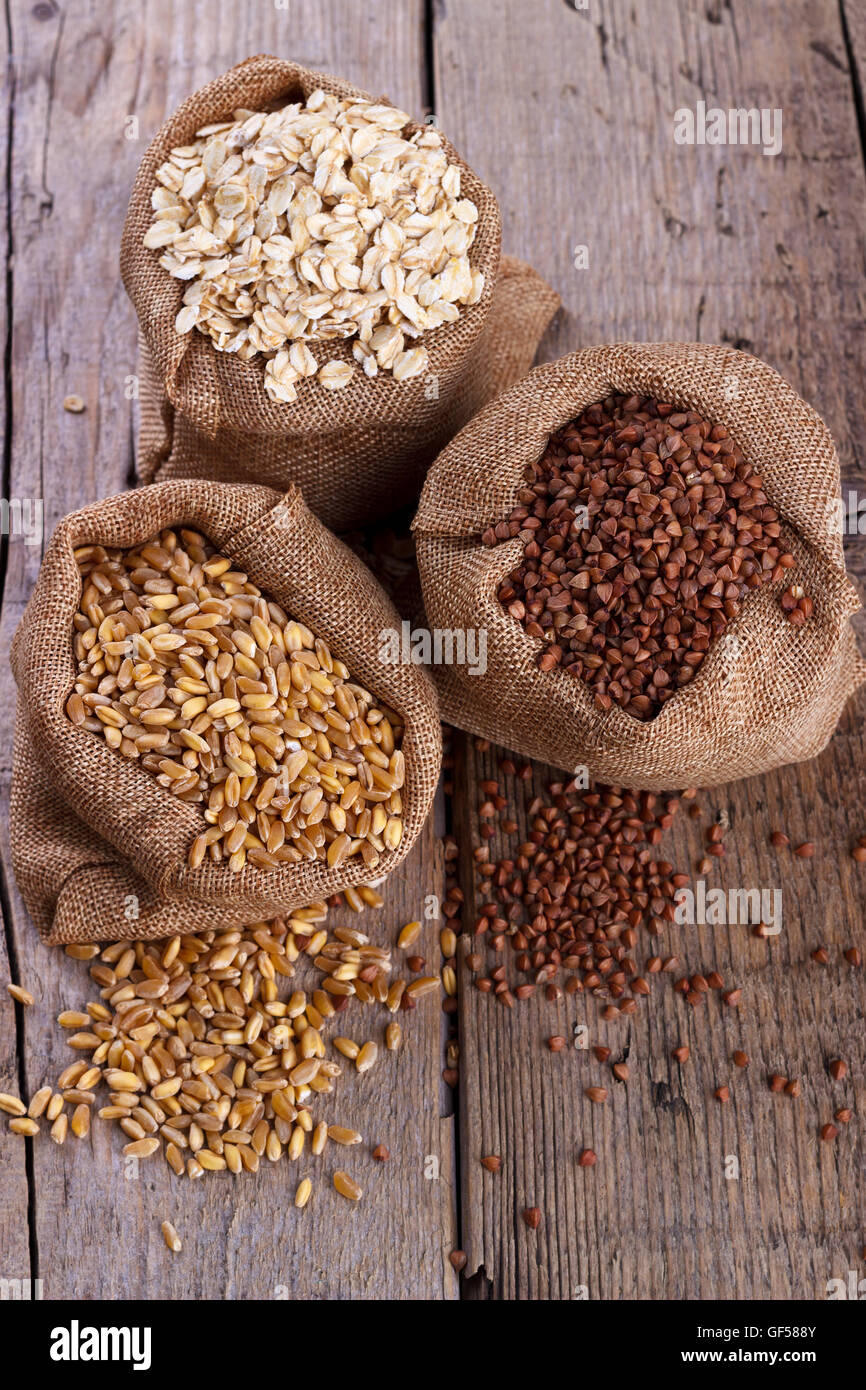 Cereals for a healthy diet, wheat,oatmeal and buckwheat in sacks on rustic wooden background