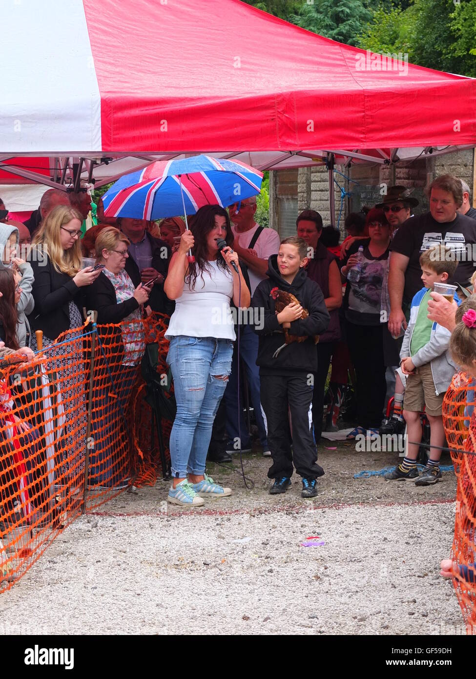 Barley Mow landlady Colette Dewhurst holding umbrella with boy competitor and hen at Bonsall World Championship Hen Racing Stock Photo
