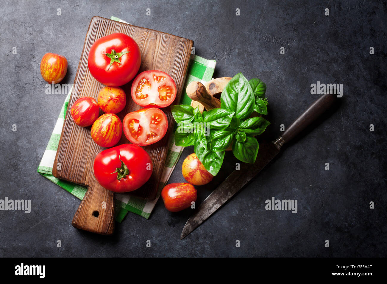 Fresh ripe garden tomatoes and basil on stone table. Top view Stock ...