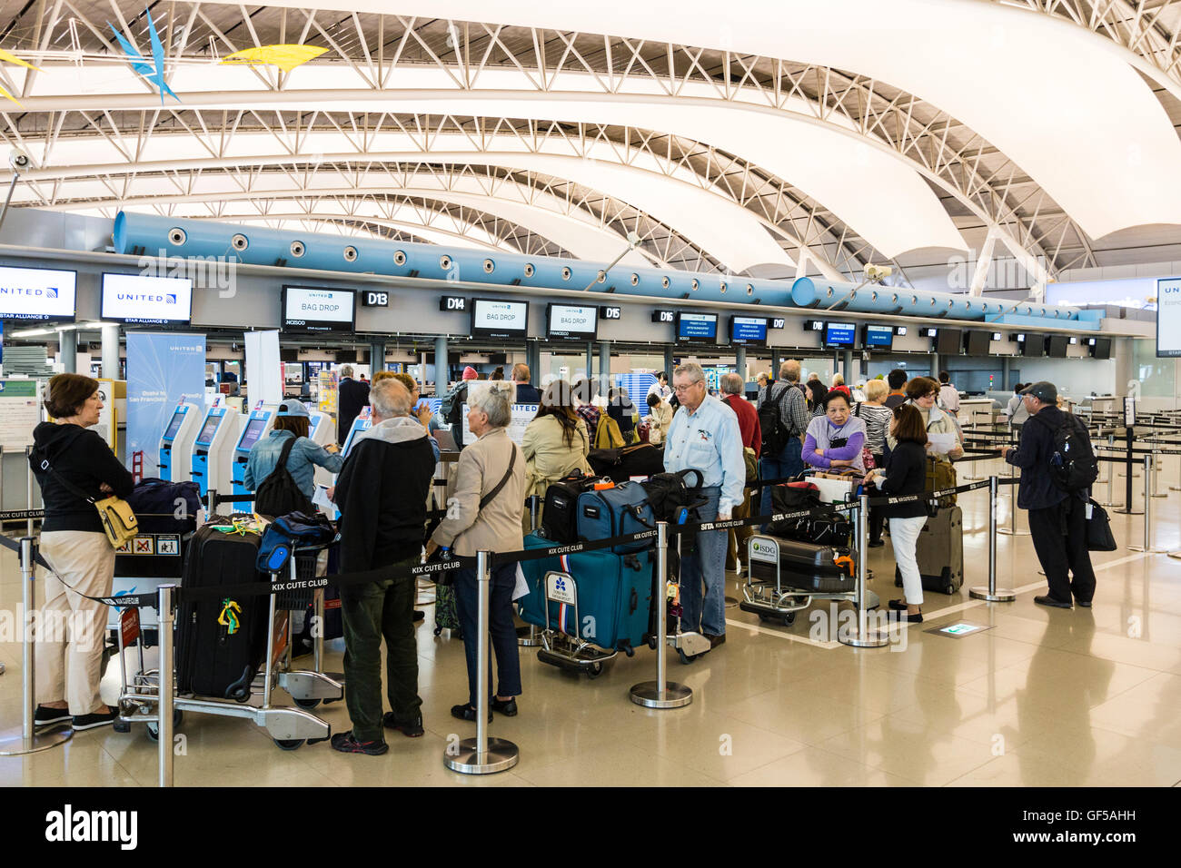 Japan, Kansai airport, KIX. Interior of terminal one. International check-in. American tourists queuing at check in desks for United airlines flight. Stock Photo