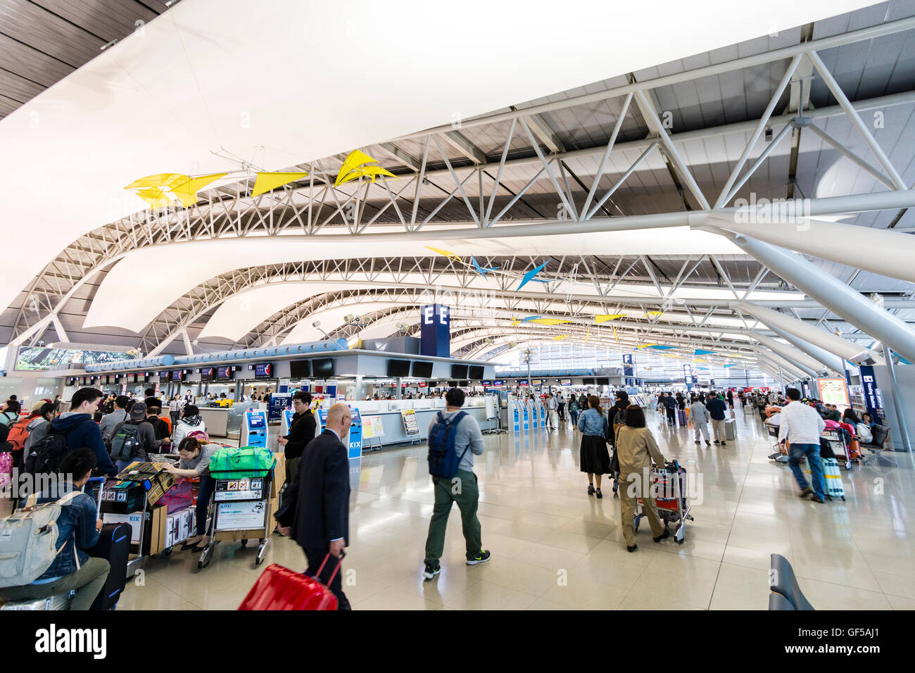 Japan, Kansai airport, KIX. Interior of terminal one building. International check-in. General view of hall with rows of check in desks and people. Stock Photo