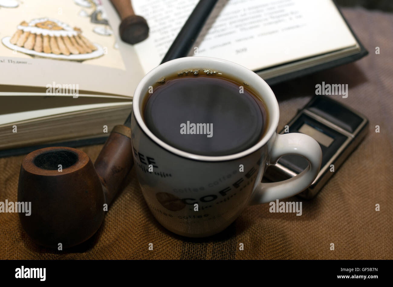 A cup of coffee with smoking pipe, a lighter and old book Stock Photo