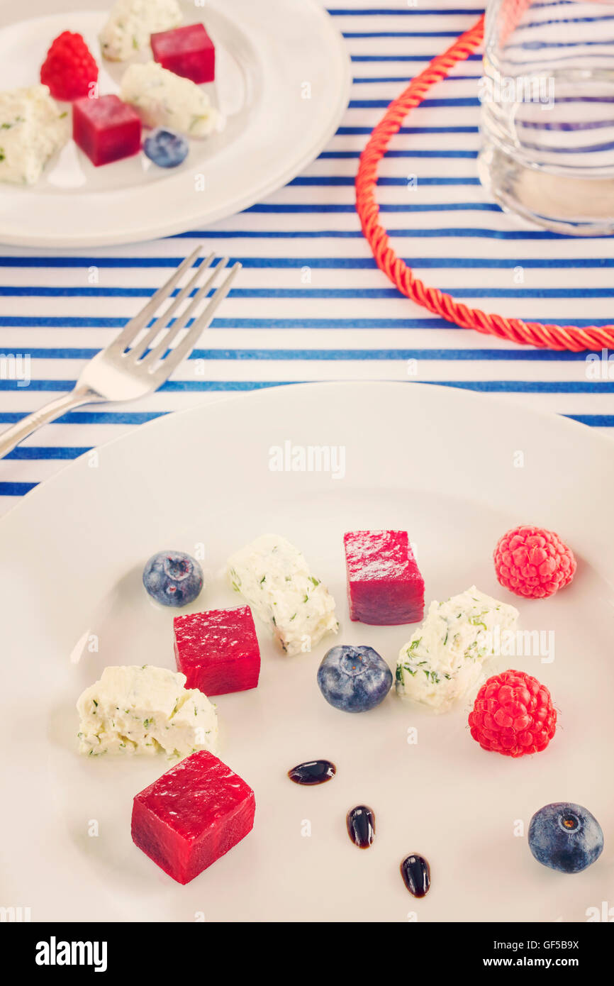 Retro toned appetizer made of beet, cottage cheese with fruits on sailing style decorated table. Stock Photo