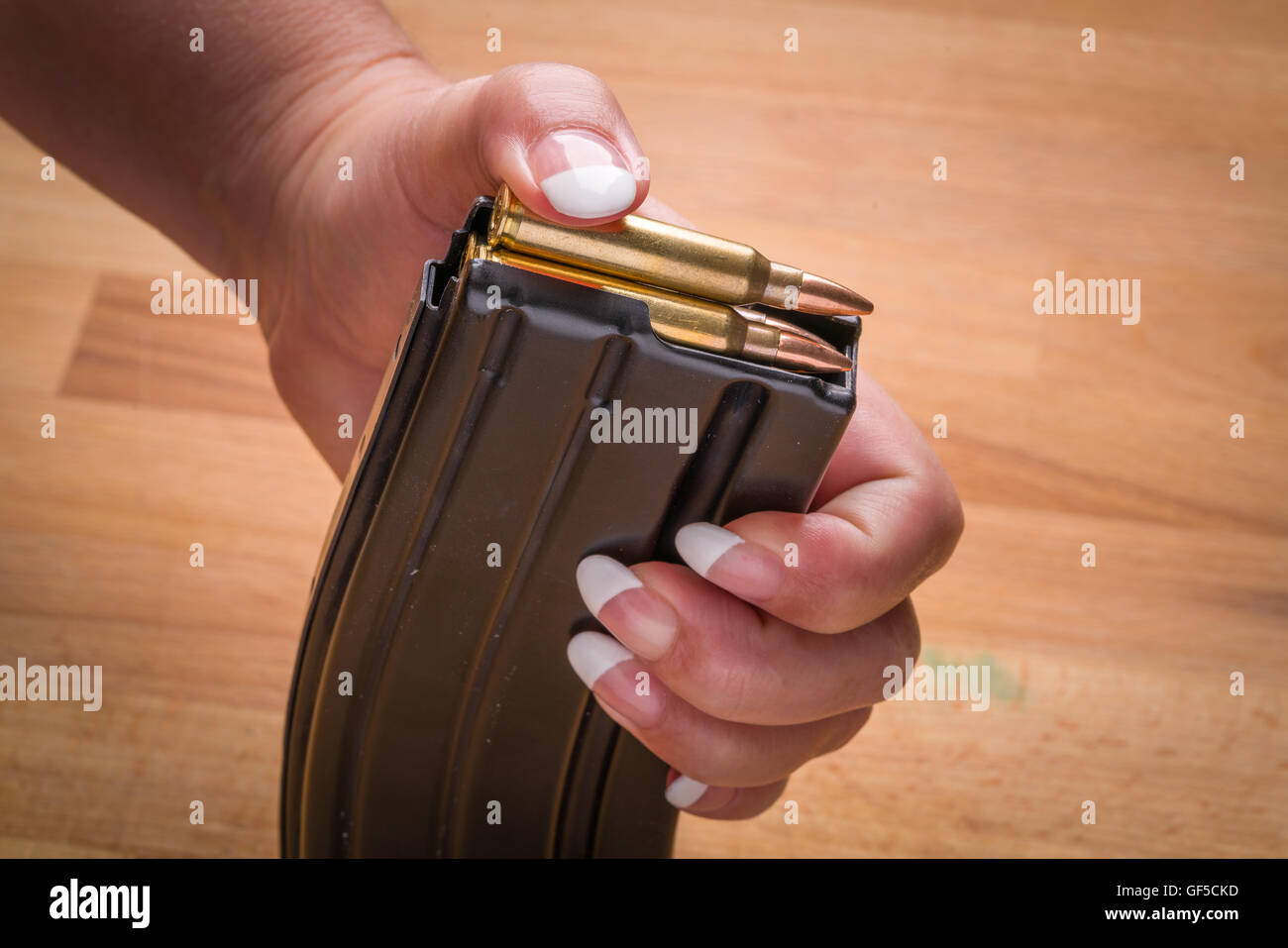 Woman Loading Ammunition in Magazine .223/556 on Wood Surface Surface