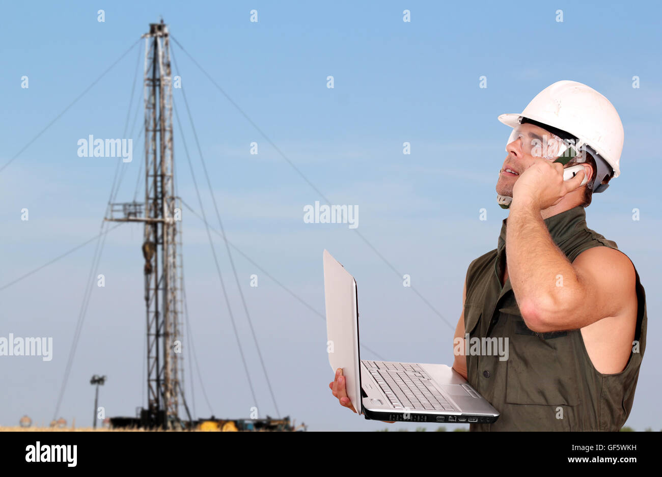 oil worker with laptop and rig Stock Photo