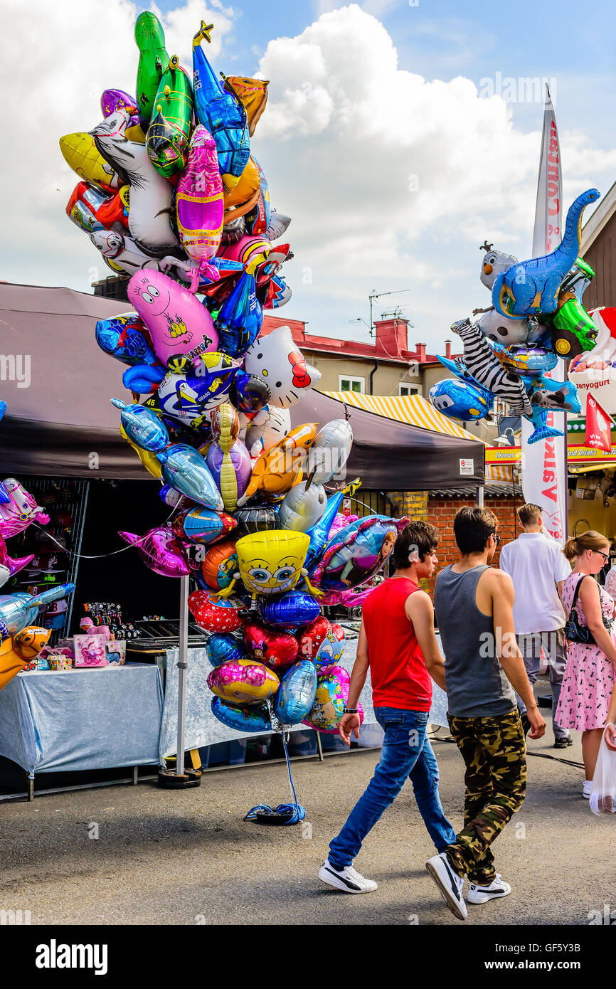 Ronneby, Sweden - July 9, 2016: Big public market day in town. People walking by a string with lots of helium filled balloons. Stock Photo