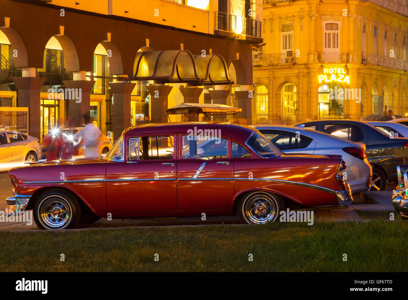 A classic American car with Hotel Plaza in the background at night in Old Havana at dusk.  Havana, Cuba. Stock Photo