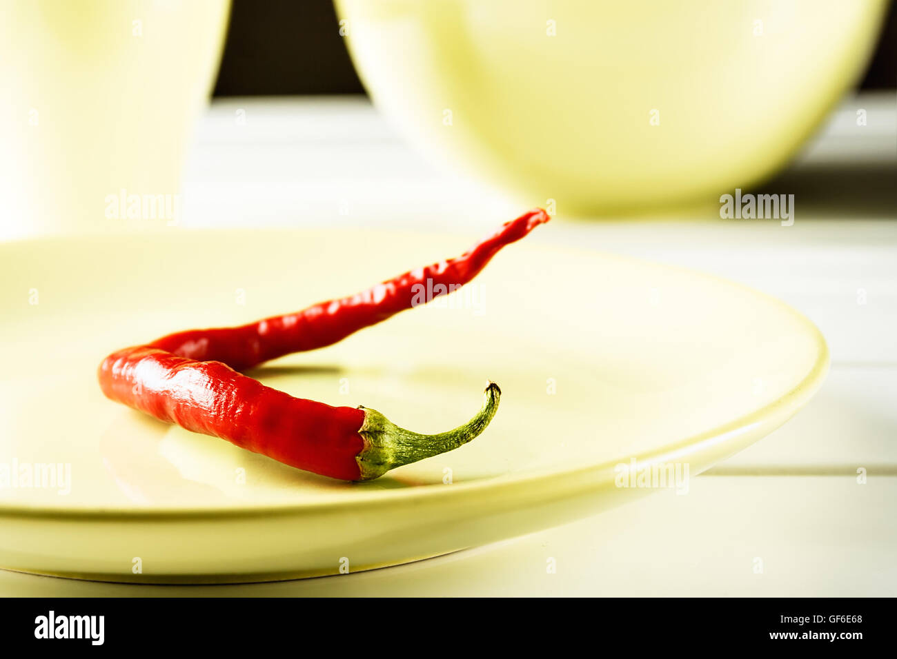 Red hot pepper on green dish over white wood. Horizontal image. Stock Photo