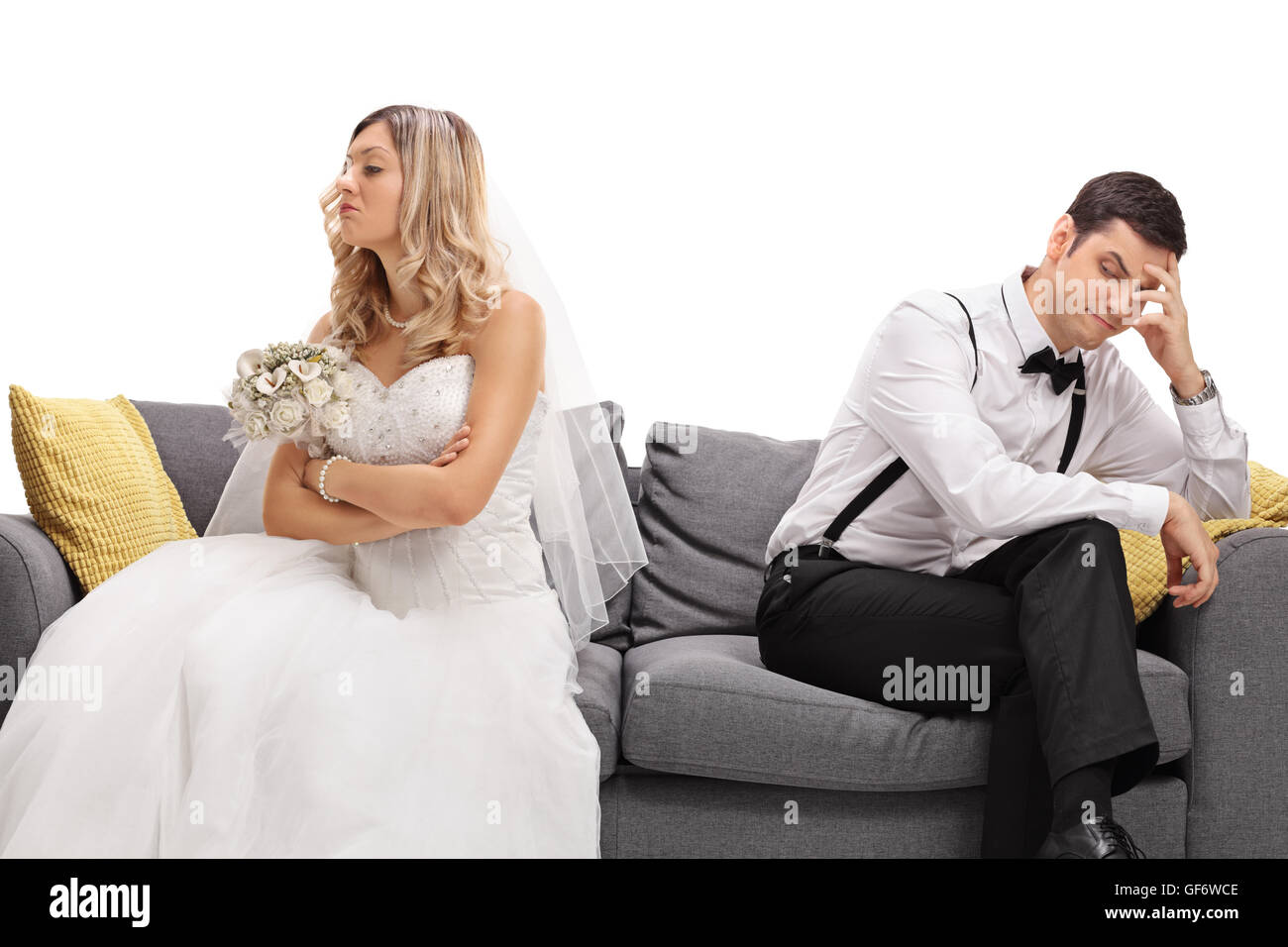 Newlywed coupe sitting on a sofa angry at each other in a middle of an argument isolated on white background Stock Photo