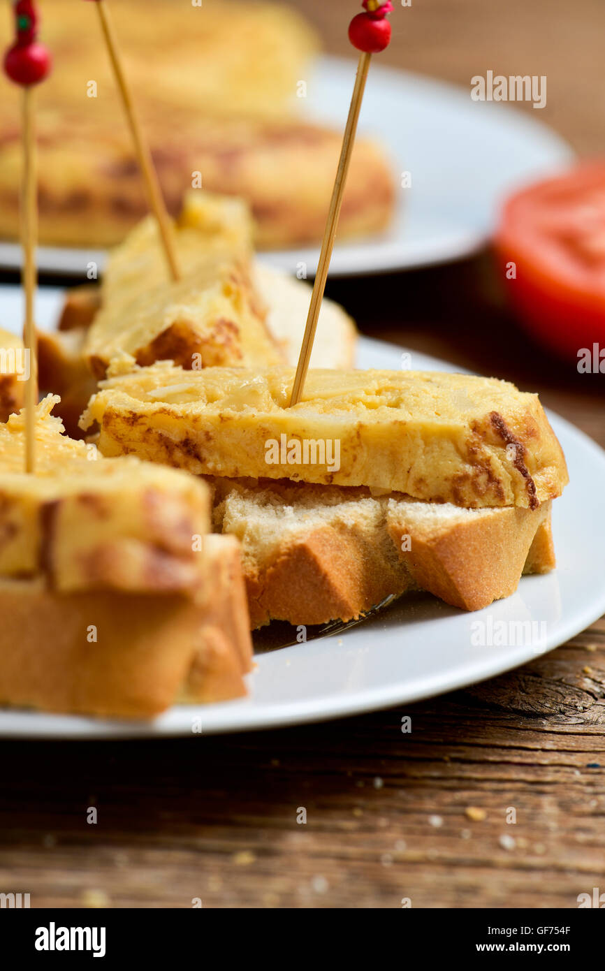 closeup of a plate with tortilla de patatas, spanish omelet, served as tapas on sliced bread and a toothpick through it, on a ta Stock Photo