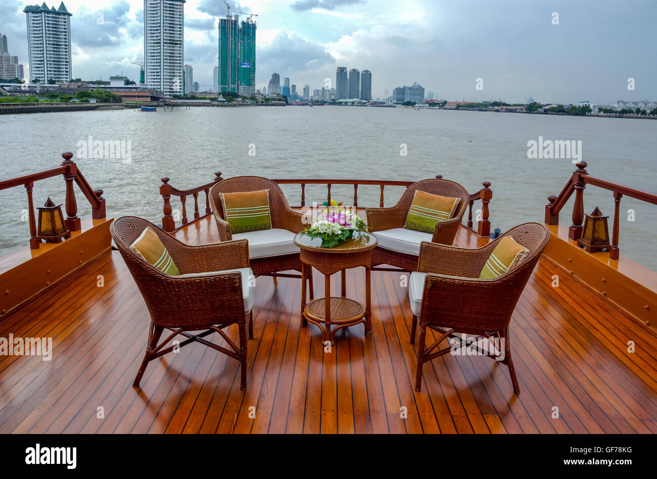 Rattan furniture, table, chairs, outdoor cushions and pillows on river boat Stock Photo