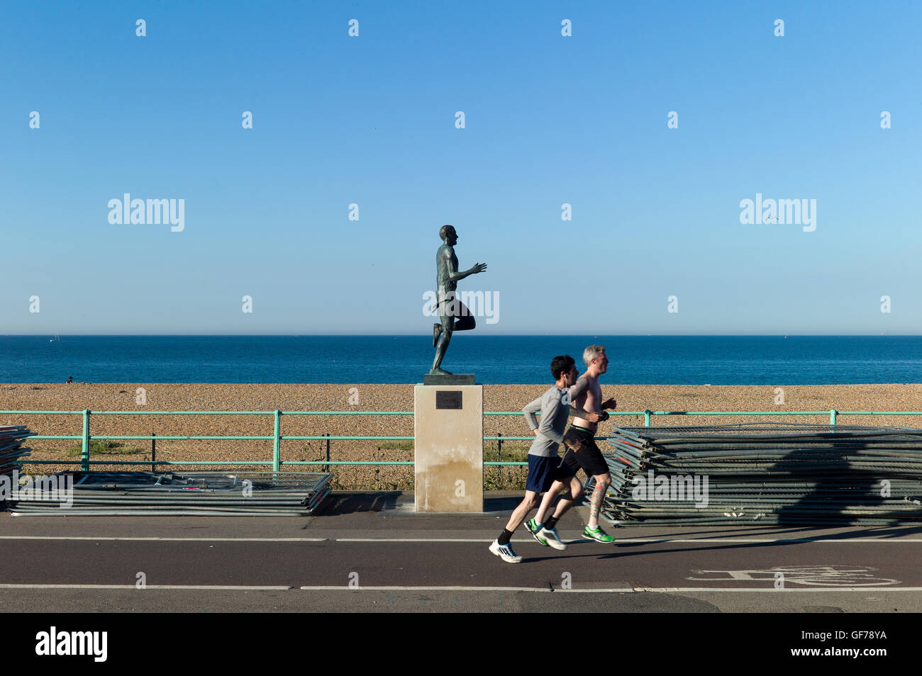 Two joggers run past statue of Olympian runner Steve Ovett, Brighton Stock Photo