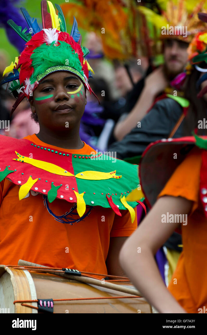 Female drummer wearing an Indian feathered headdress taking part in the Carnival Parade, part of the Edinburgh Jazz Festival. Stock Photo