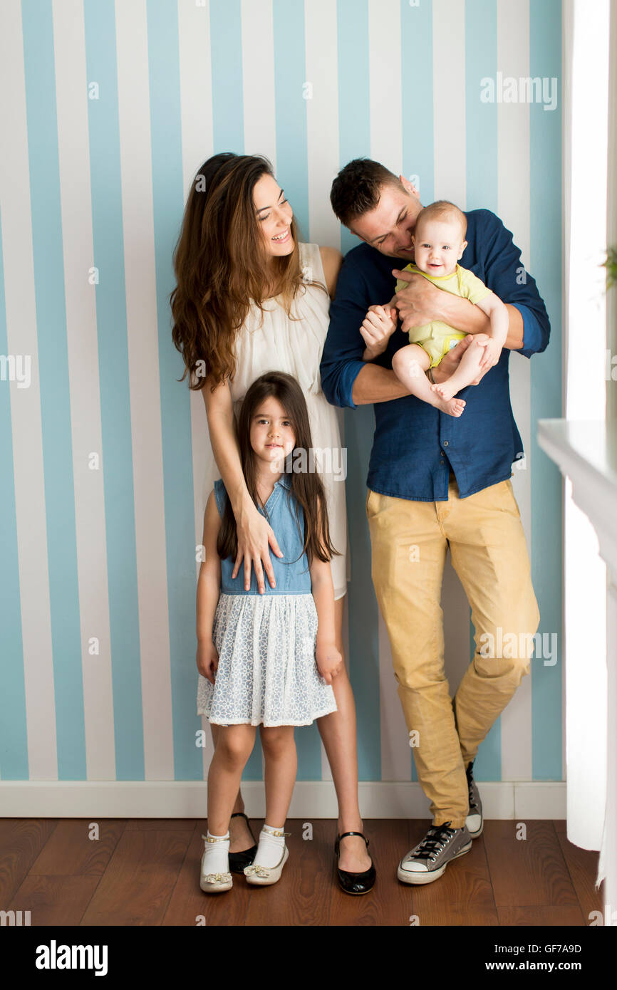 Young family standing side by side by the wall Stock Photo