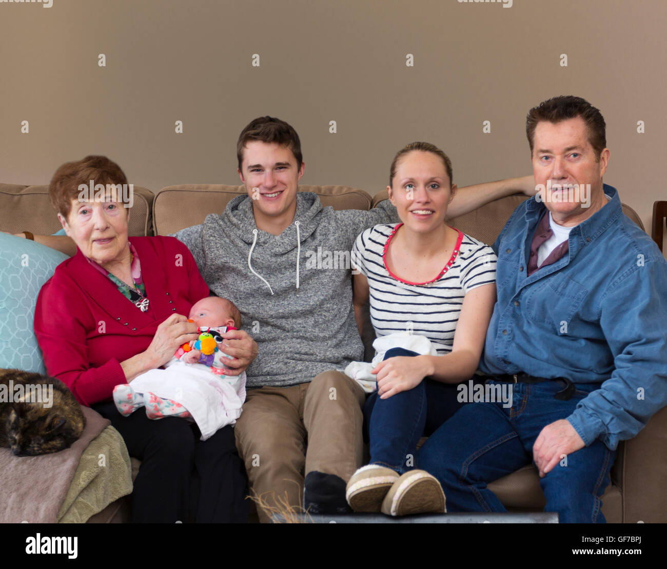 4 generations of people, multi generations of people sitting on sofa with baby Stock Photo