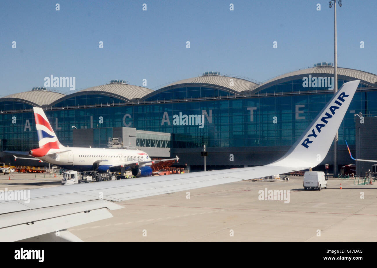 Wing of an airplane of the airline Ryanair passes a British Airways plane at the gangway of Alicante Airport Stock Photo