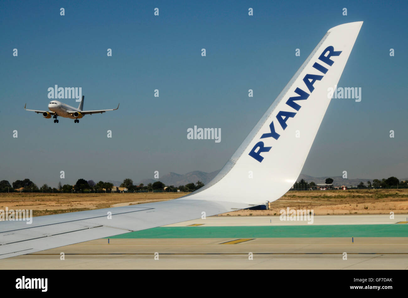 Wing of an airplane of the airline Ryanair waiting on an airplane landing  on the runway of the airport of Alicante Stock Photo