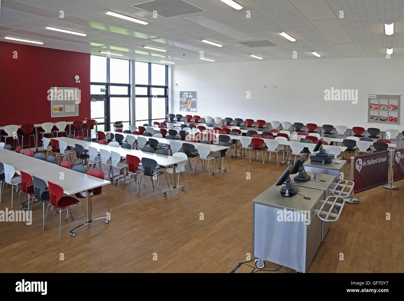 Interior view of a new school dining hall. Shows tables and chairs, serving area, no people. Stock Photo