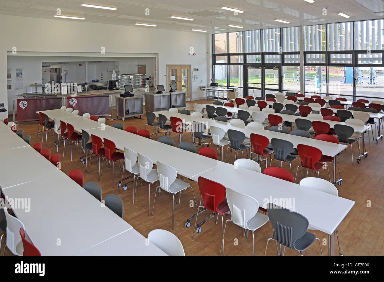 Interior view of a new school dining hall. Shows tables and chairs, kitchen area, no people. Stock Photo