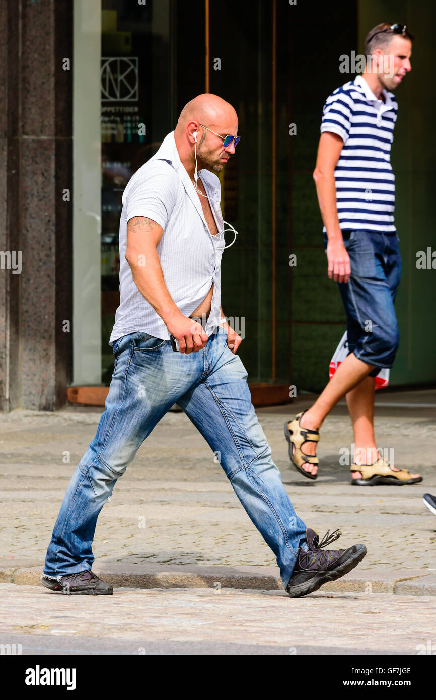 Goteborg, Sweden - July 25, 2016: Unknown male walking by on the sidewalk with a very hard and tense style while listening in ea Stock Photo